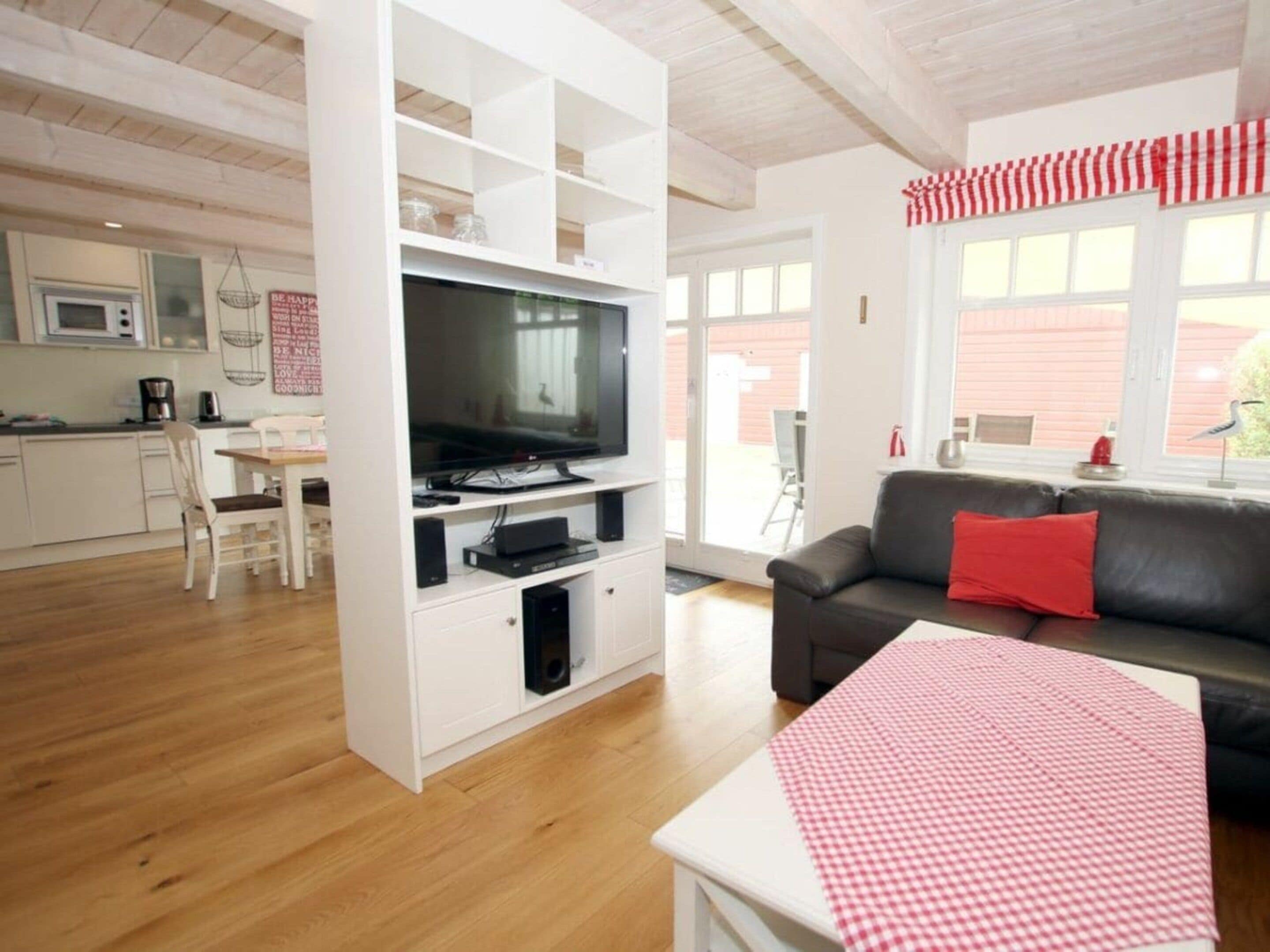 A compact living space with a kitchenette, a flat-screen TV, a sofa, and a dining area.