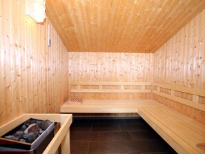 En sauna med træbænke og stengulv.
