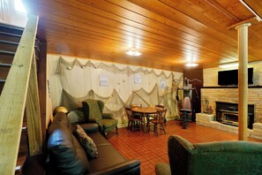 A cozy room with a wooden ceiling, a fireplace, a television, and a dining table with chairs. - Entire house located on the Shenandoah River (Harpers Ferry)