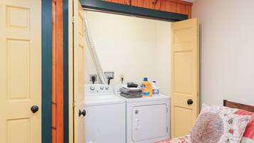 A laundry room with a washing machine and dryer, a drying rack, and laundry supplies.