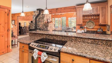 A kitchen with granite countertops, a stove, and wooden cabinetry.