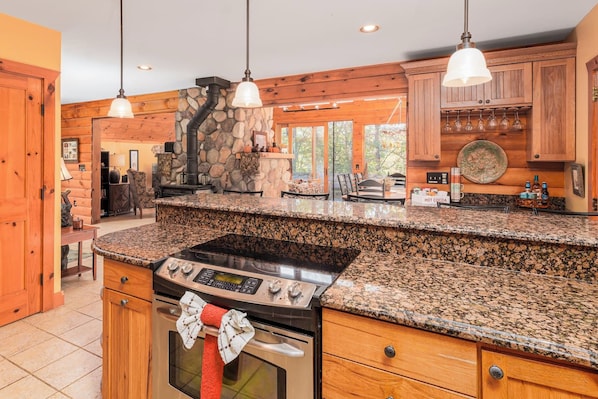 A kitchen with granite countertops, a stove, and wooden cabinetry.