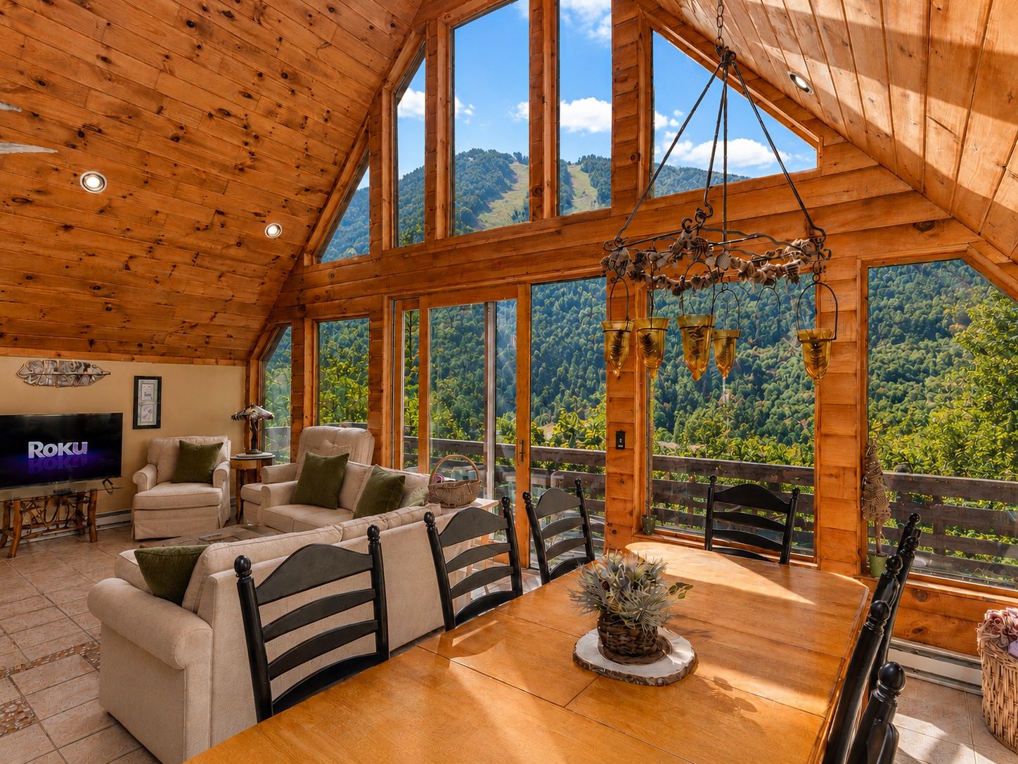 A wooden interior with a TV, sofas, and a dining table with chairs.