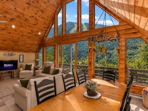 A wooden interior with a TV, sofas, and a dining table with chairs.