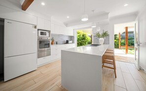 A modern kitchen with white cabinetry, stainless steel appliances, and a large island with bar stools.