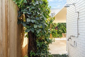 A covered outdoor area with a wooden fence, a white brick wall, and a shower area.