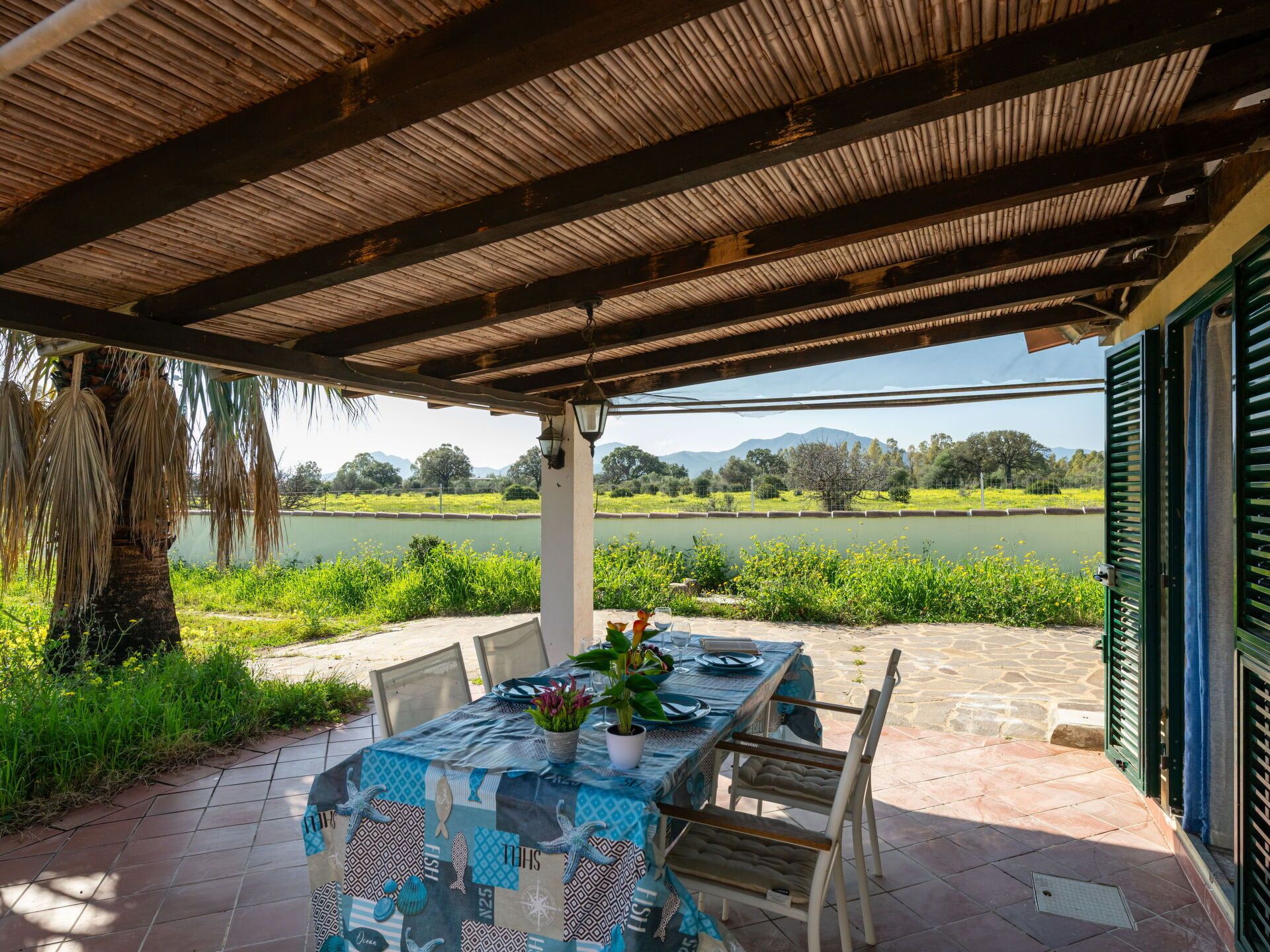 An outdoor dining area with a table set for two, overlooking a lake and greenery.