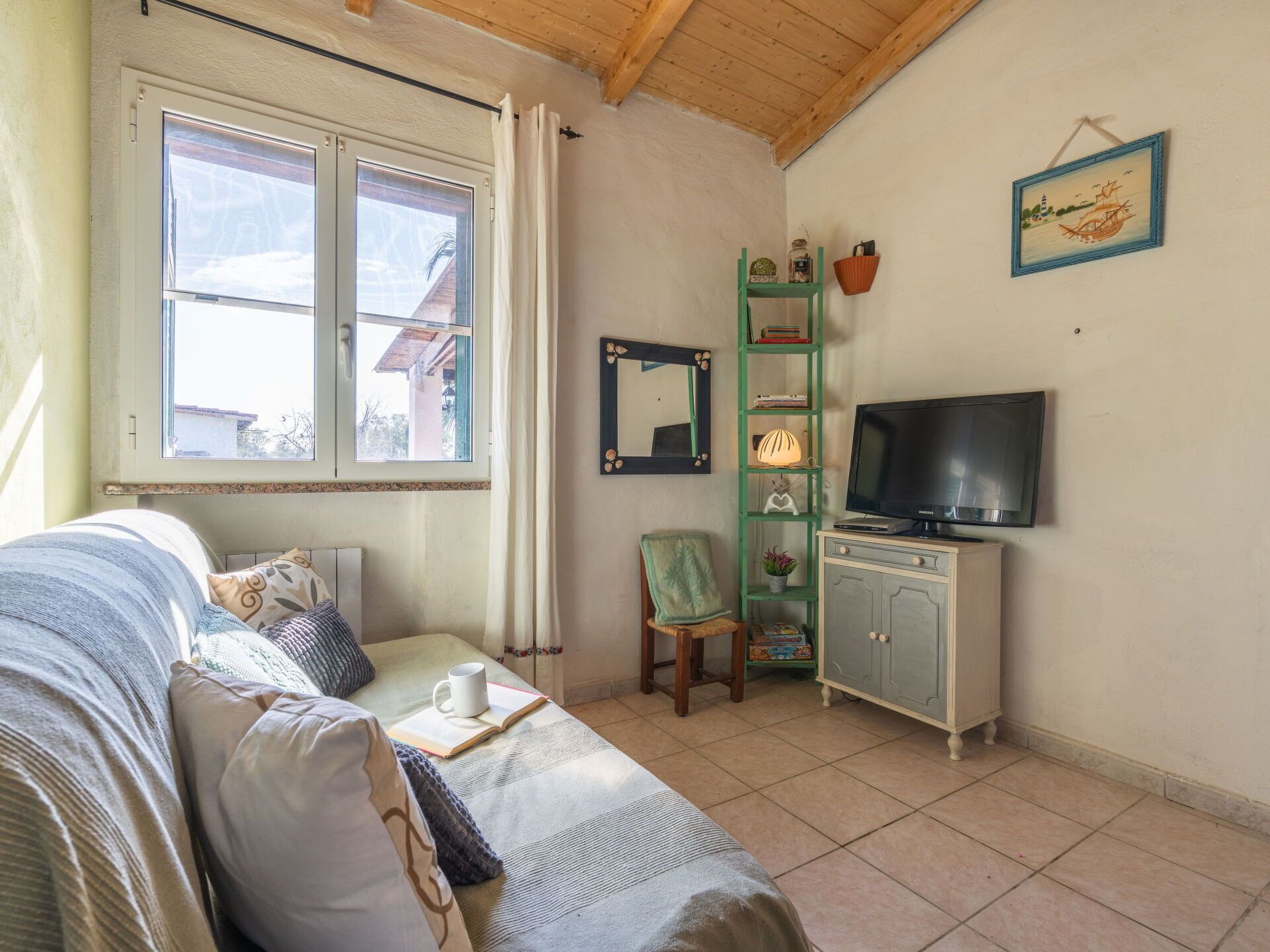 Une pièce confortable avec un lit, une télévision, une bibliothèque et une fenêtre avec des rideaux.