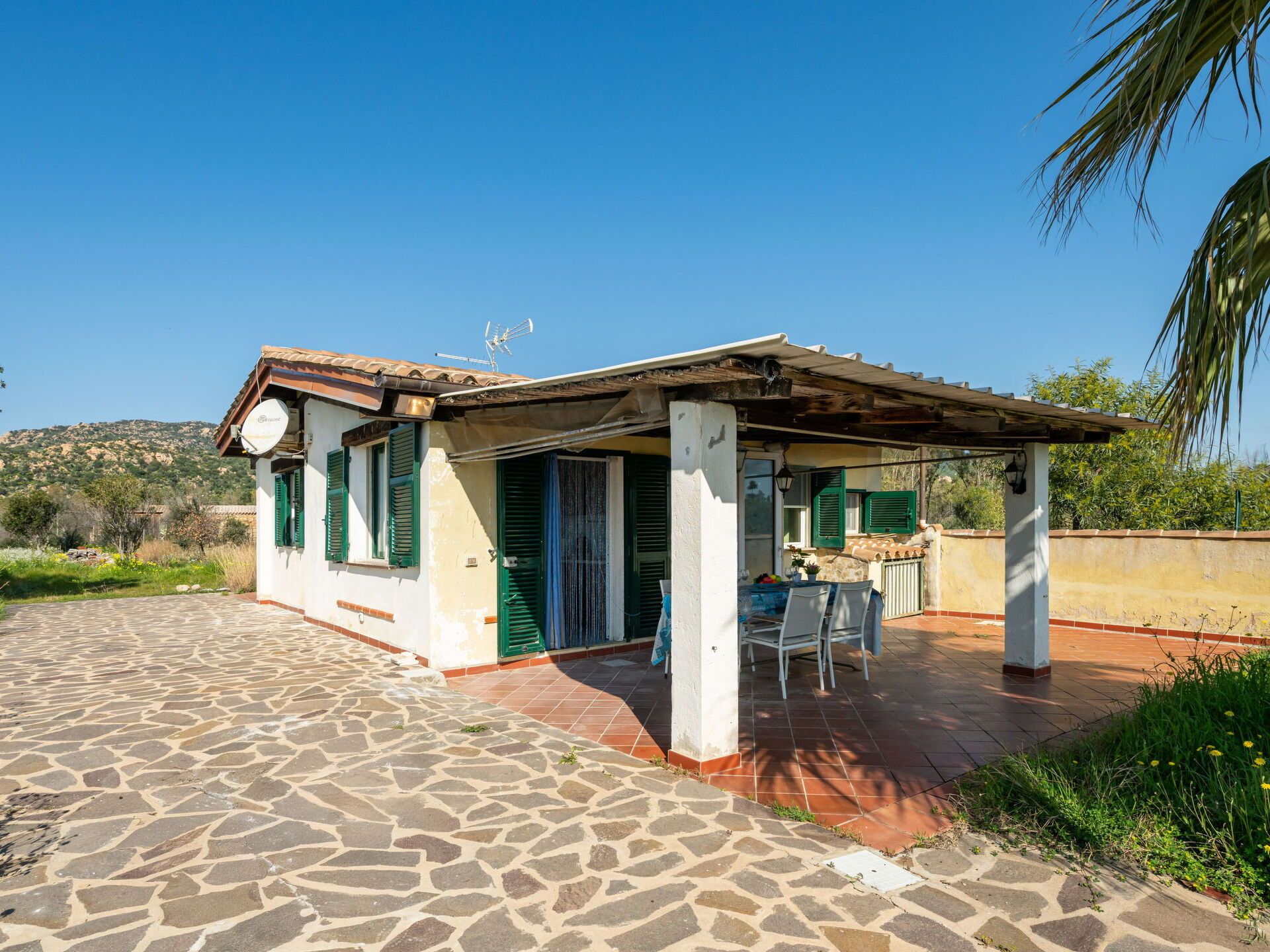 Una casita con patio de baldosas y zona de estar cubierta al aire libre.