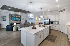 A modern kitchen with white cabinetry, a central island, and a built-in oven. - Pool Home In Calusa Golf & Country Club - Fore Seasons (Bradenton)