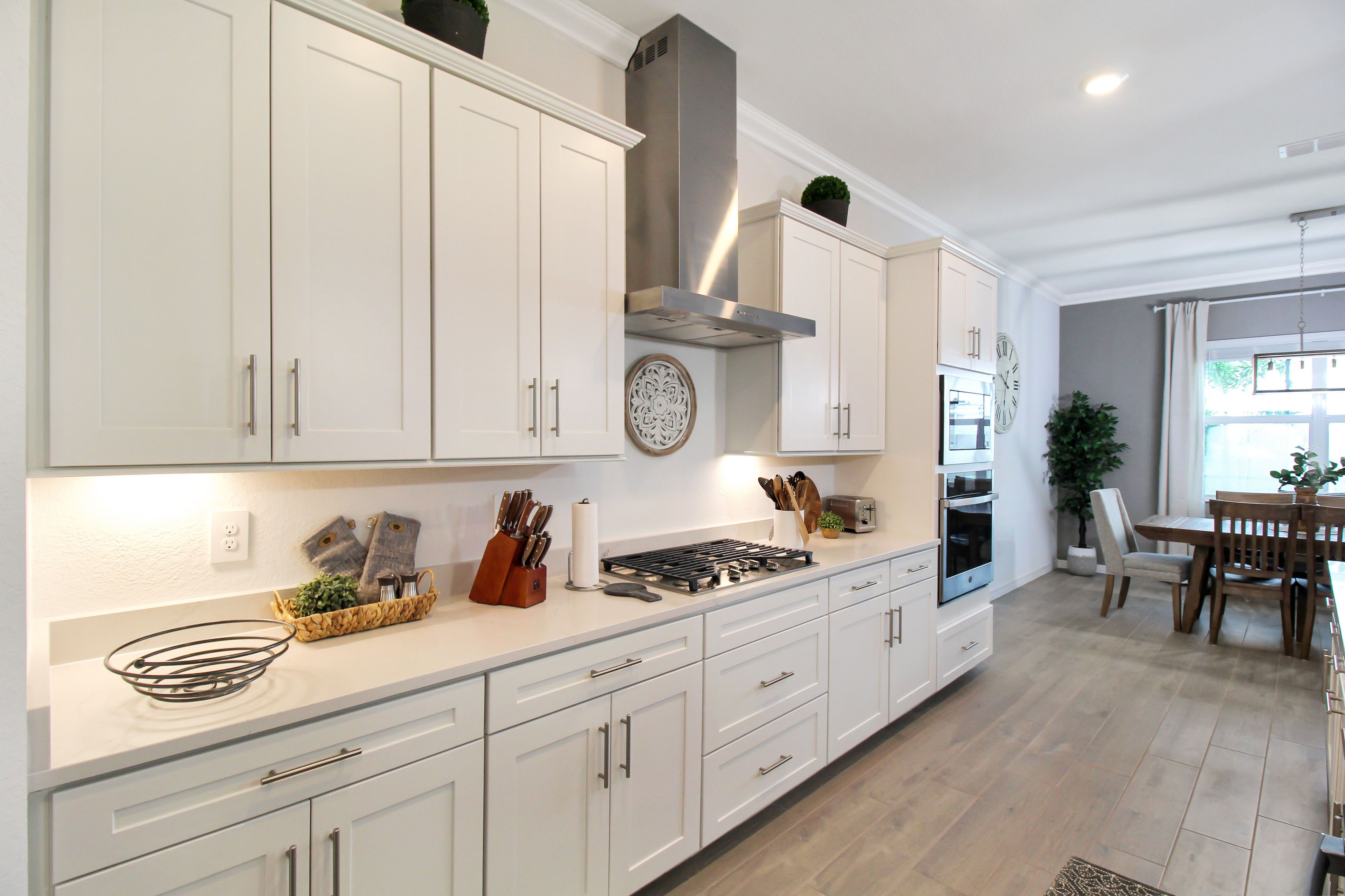 A modern kitchen with white cabinetry, a gas stove, and a built-in oven.