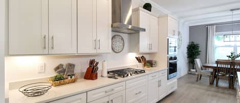 A modern kitchen with white cabinetry, a gas stove, and a built-in oven.