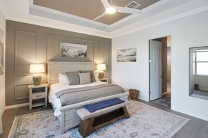 A bedroom with a bed, bedside tables, lamps, a bench, and artwork on the walls. - Pool Home In Calusa Golf & Country Club - Fore Seasons (Bradenton)