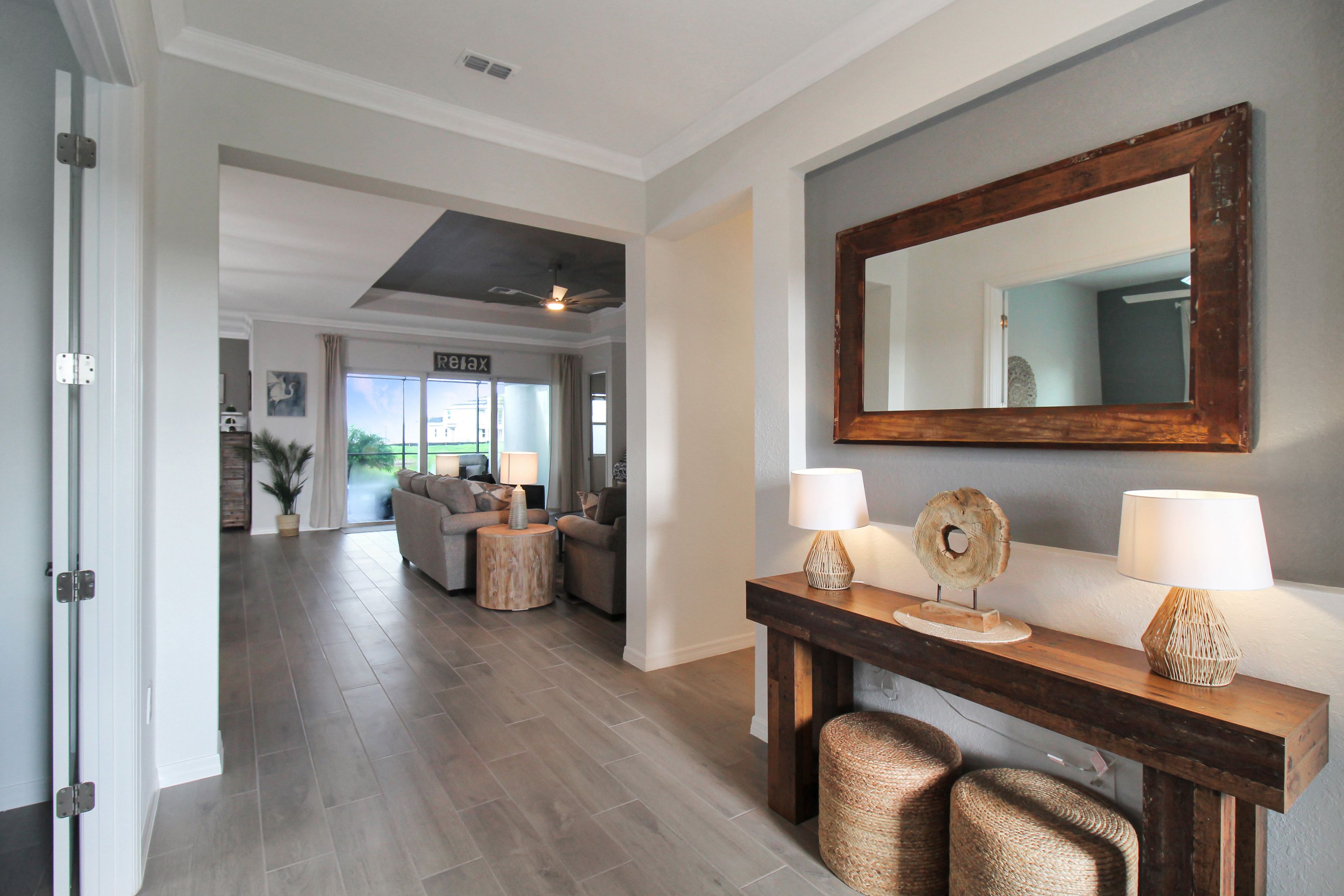 A modern living room with a wooden console table, two lamps, and a large mirror.