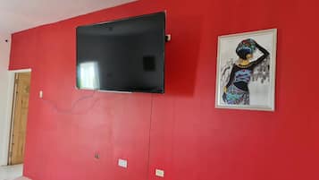 Un mur rouge orné d’un téléviseur à écran plat et d’une œuvre d’art encadrée.