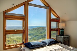 Un dormitorio con un ventanal que ofrece vistas a un paisaje boscoso.