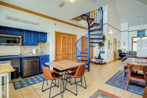 Una cocina moderna con armarios azules, una mesa de comedor de madera con sillas y una escalera de caracol.