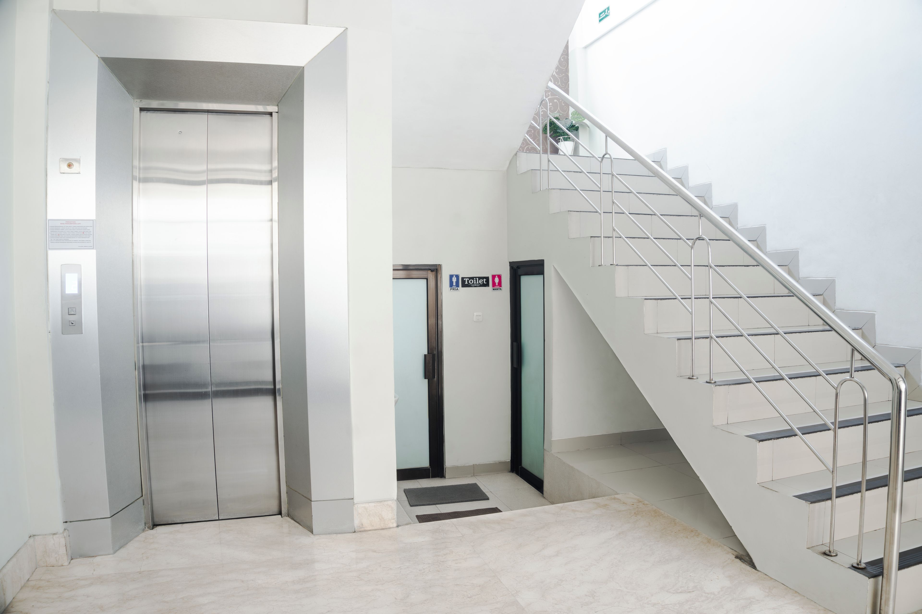 Een lift, een trap en een bordje met daarop een toilet.