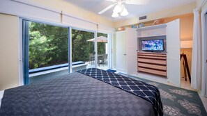 A bedroom with a bed, a television, and a sliding glass door leading to a patio. - 811 Mariner's Club | Luxury Resort affordably priced (Key Largo)
