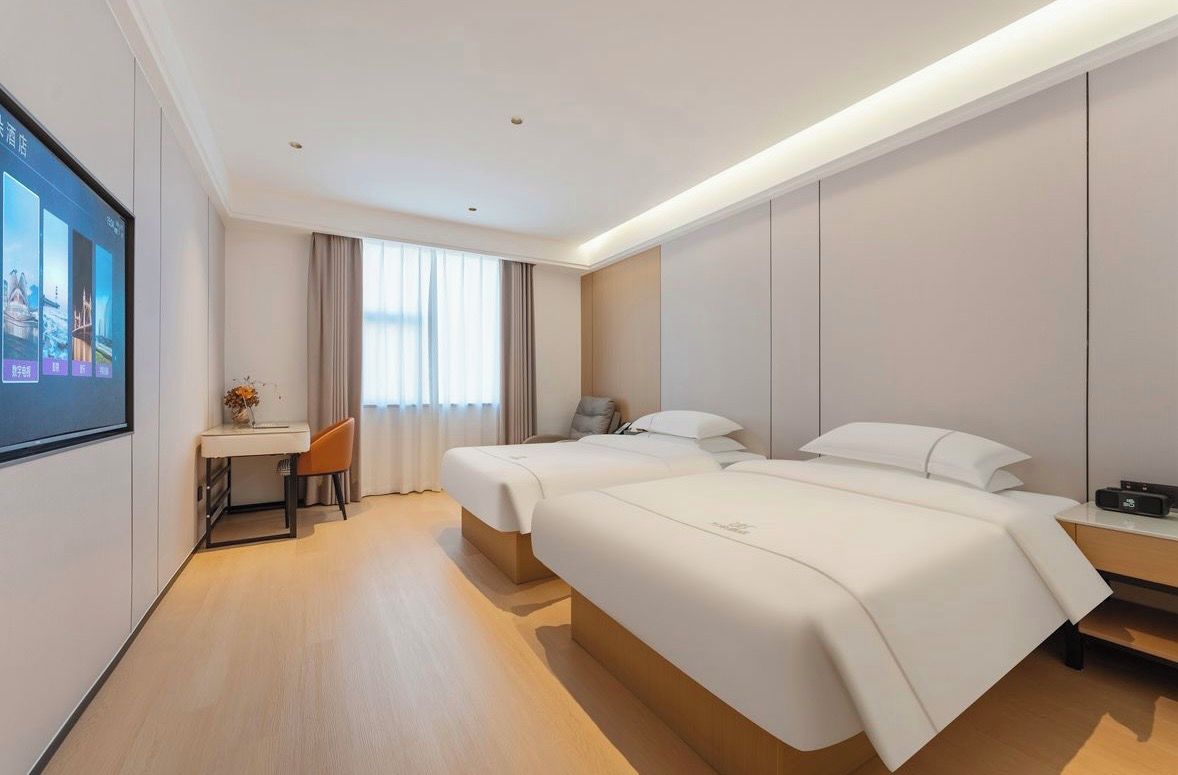 Habitación de hotel con dos camas, un escritorio y televisión.