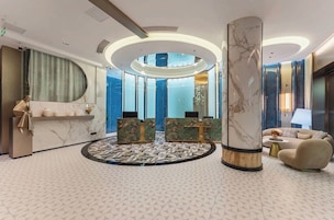A modern lobby with a marble reception desk, a round seating area, and a sofa.