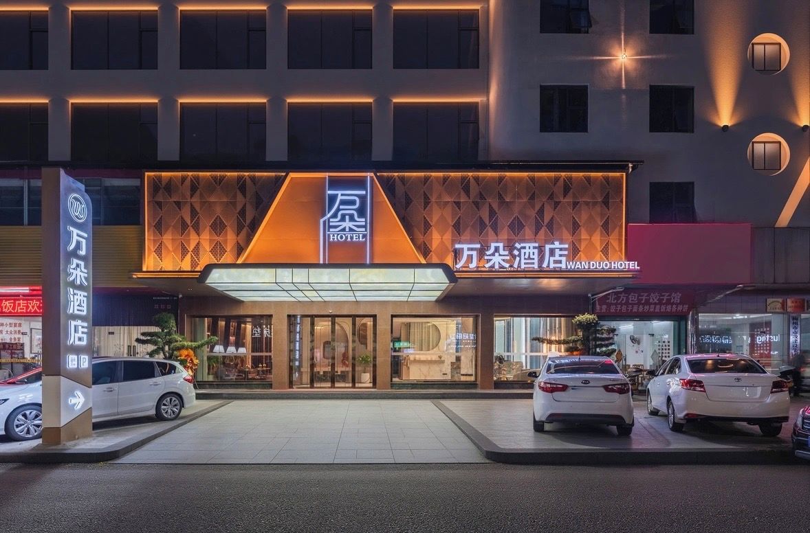 A hotel with a modern facade, large glass entrance, and multiple cars parked in front.