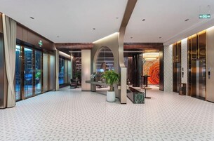 Un moderno vestíbulo de hotel con piso de diseño geométrico, un área de estar central y un gran mural en la pared.