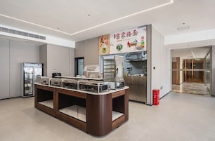 A modern kitchen area with a buffet setup, a refrigerator, and a microwave.