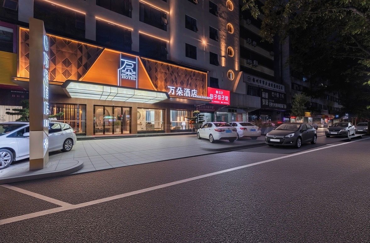 Un hotel con una fachada moderna, varios pisos y un estacionamiento con varios coches.