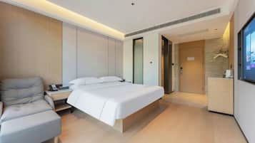 A modern hotel room with a bed, a sofa, a desk with a telephone, and a television.
