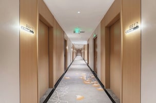 Corredor de hotel com portas de madeira, numeradas 8813 e 8812, e um tapete com padrão de folhas.