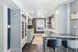 Una cocina moderna con una isla central, iluminación colgante y vistas al área de comedor.