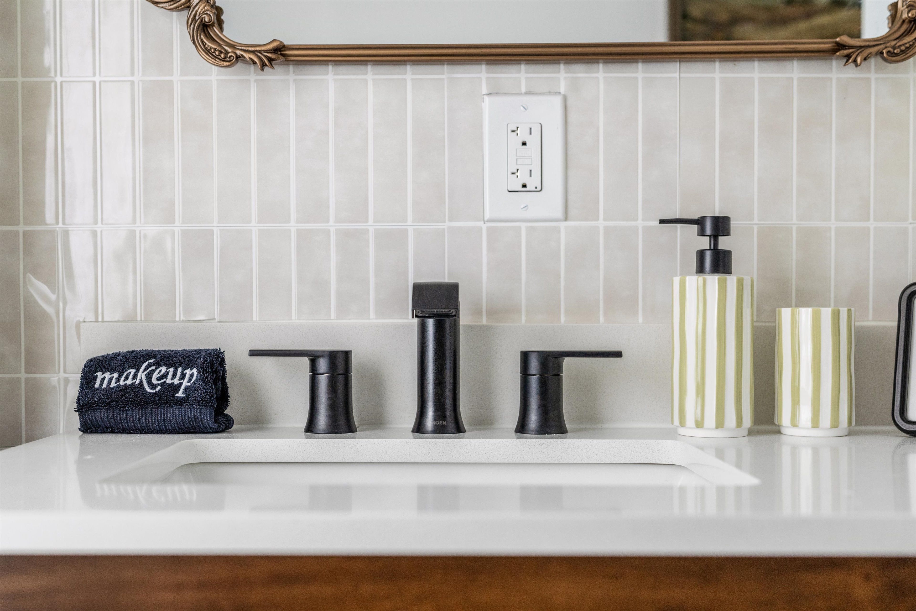A bathroom vanity with a towel, a faucet, a soap dispenser, and a cup.