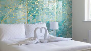 A neatly made bed with white linens and pillows, a bedside lamp, and a wall with a geometric pattern.