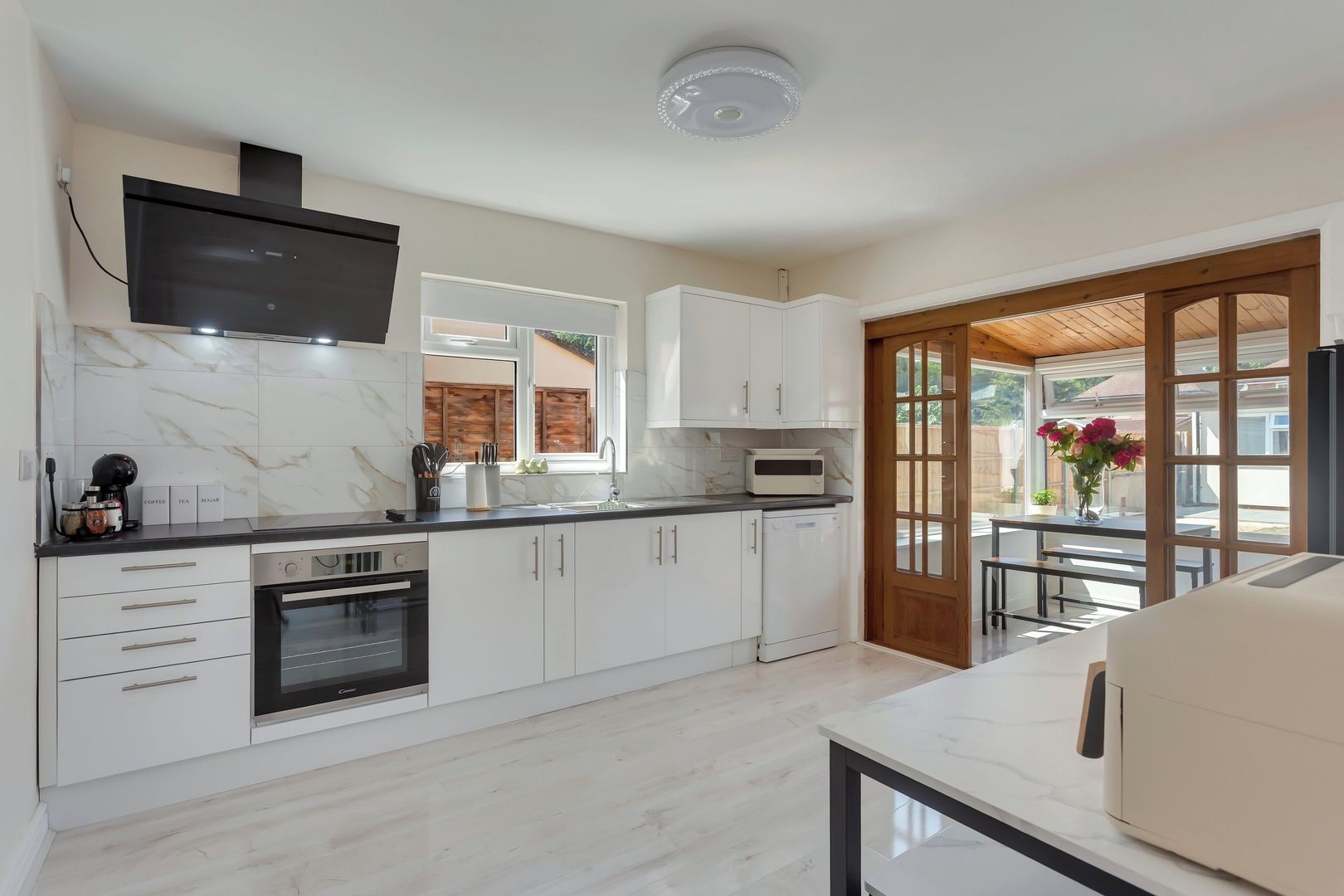 A modern kitchen with white cabinets, a built-in oven, and a microwave.