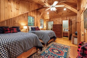A cabin with two beds, a ceiling fan, and a large window. - Todd Hideaway Overlooking Creek - Hot Tub, Fire Pit, Game Room (Todd)