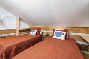 A room with two beds, each with a pillow featuring a bear design. - Todd Hideaway Overlooking Creek - Hot Tub, Fire Pit, Game Room (Todd)