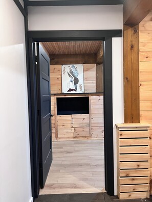 Een open deuropening die leidt naar een kamer met houten wanden en een zwarte deur.