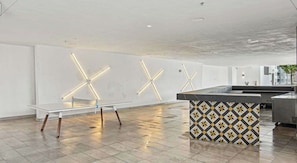 A modern interior with a glass table, a patterned bar area, and geometric wall lighting. - Downtown Miami Studio with Balcony & Pool (Miami)