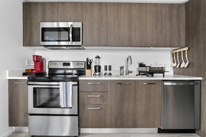 A modern kitchen with stainless steel appliances, wooden cabinets, and a dishwasher. - Downtown Miami Studio with Balcony & Pool (Miami)