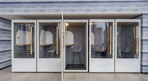 A modern interior with four enclosed spaces, each with a chair and a small table. - Downtown Miami Studio with Balcony & Pool (Miami)