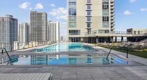 A rooftop pool with a view of high-rise buildings, lounge chairs, and a clear sky. - Downtown Miami Studio with Balcony & Pool (Miami)