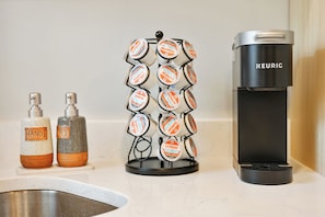 A kitchen counter with a coffee maker, a soap dispenser, and a mug holder with Dunkin' branded items.