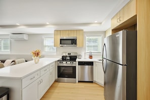A modern kitchen with white cabinetry, stainless steel appliances, and a central island.