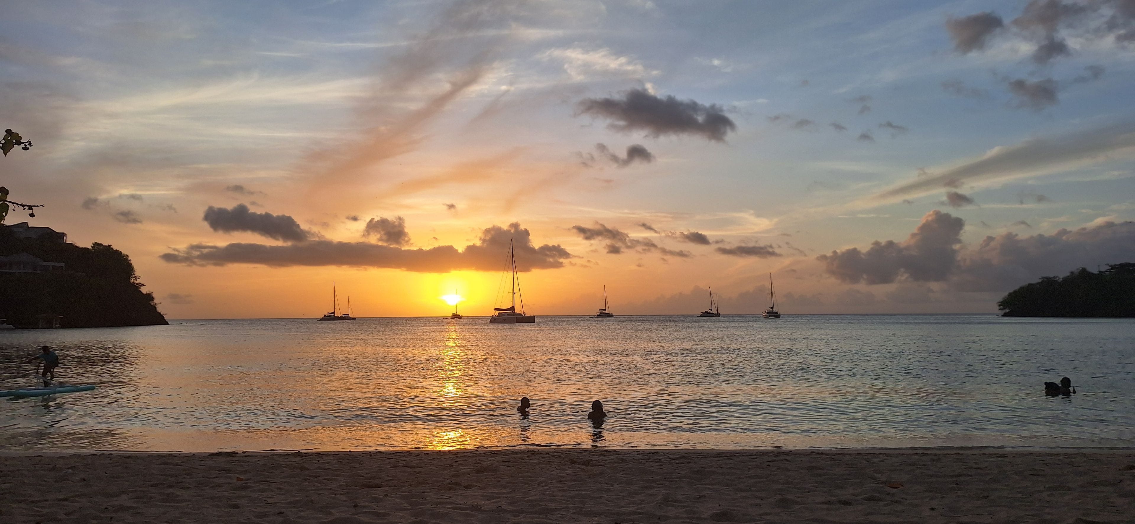 A beach with boats and a sunset.