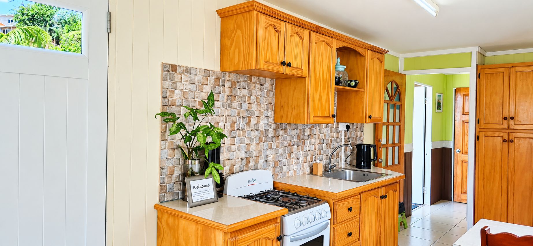 A kitchen with wooden cabinets, a stone backsplash, a stove, and a sink.
