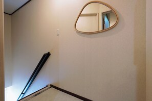 A corner of a room with a mirror on the wall, a door, and a staircase with a handrail. - Family-Friendly Home｜5min to USJ｜Near Nishikujo (Osaka)