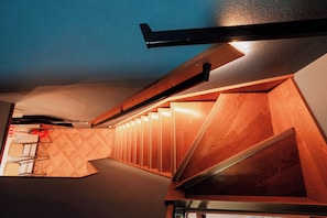 Een modern interieur met een houten trap en een geometrisch patroon op de muur.