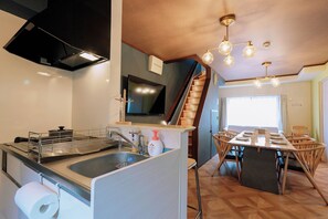 A kitchen with a built-in stove, sink, and a dining area with a table and chairs. - Family-Friendly Home｜5min to USJ｜Near Nishikujo (Osaka)