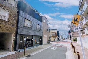 A narrow urban street with residential buildings, a pedestrian crossing sign, and a clear sky. - Family-Friendly Home｜5min to USJ｜Near Nishikujo (Osaka)